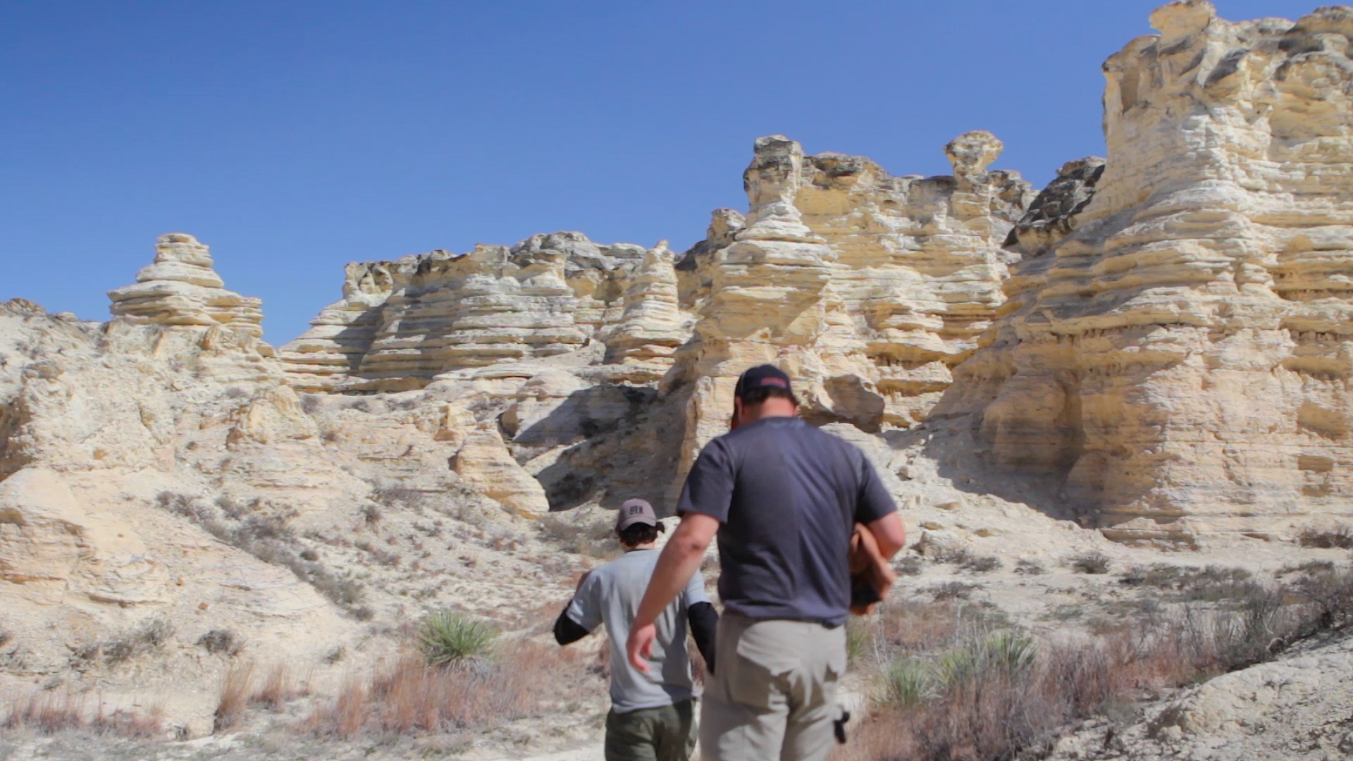 Few people walking with rocks surrounded.