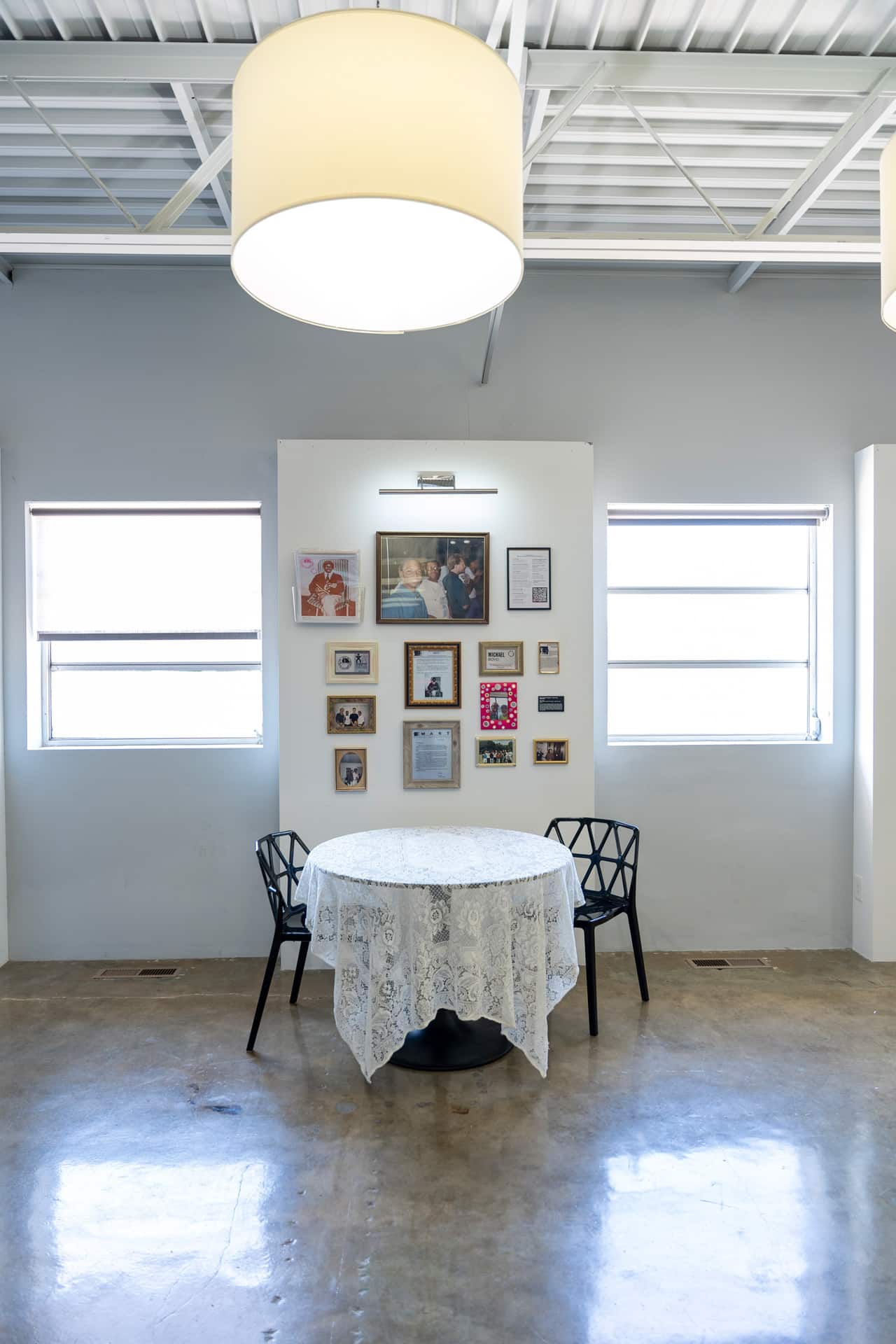 table and 2 chairs with an exhibit of framed photos and documents behind it