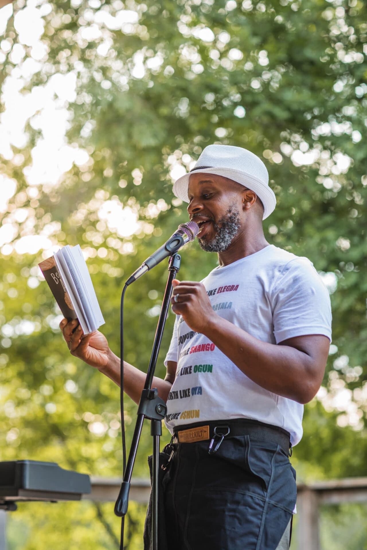 male reciting poem from book in mic on stage