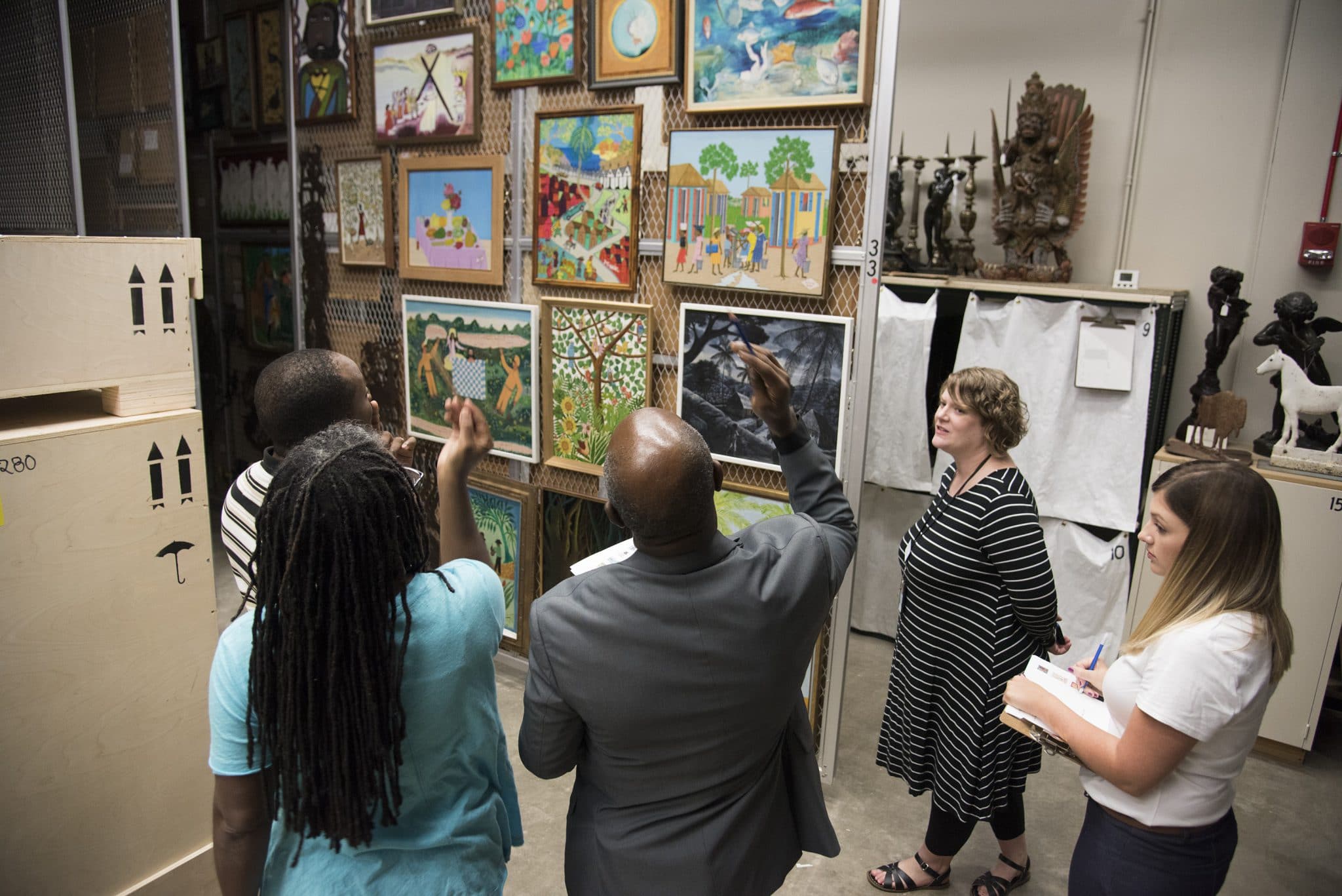 4 people looking at the paintings on wall and discussing