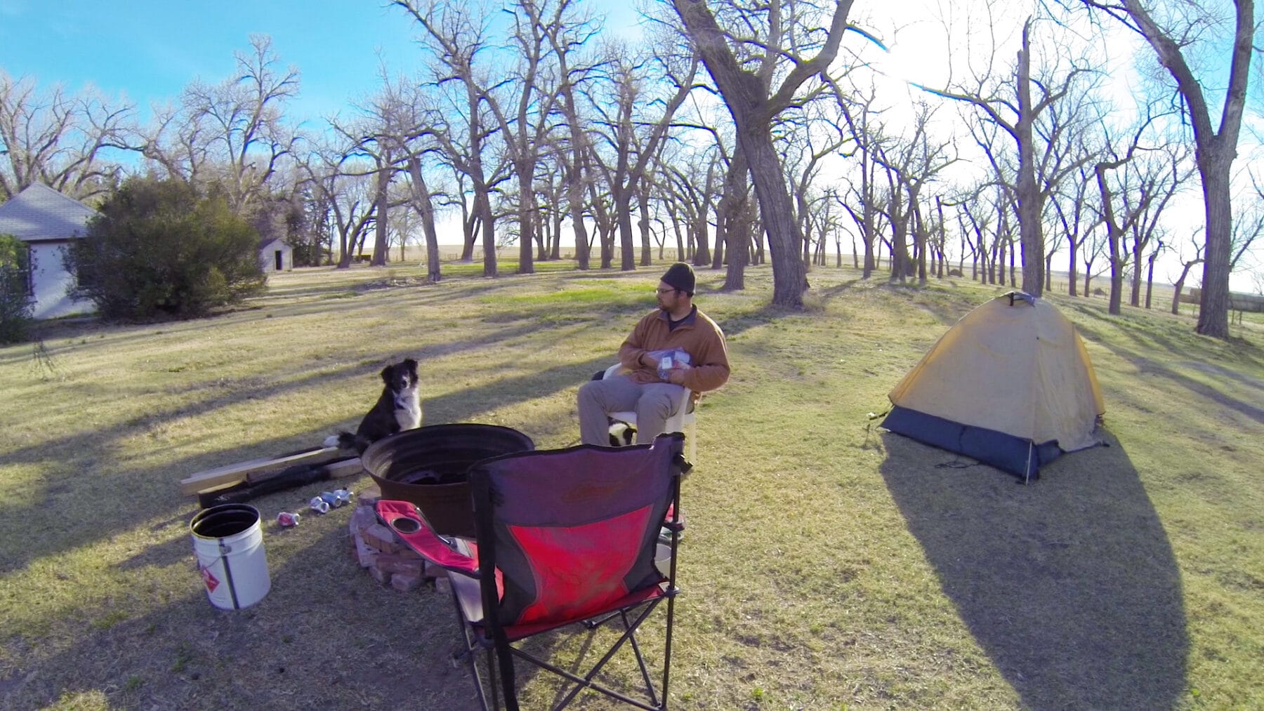 A man looking at a dog at a campsite