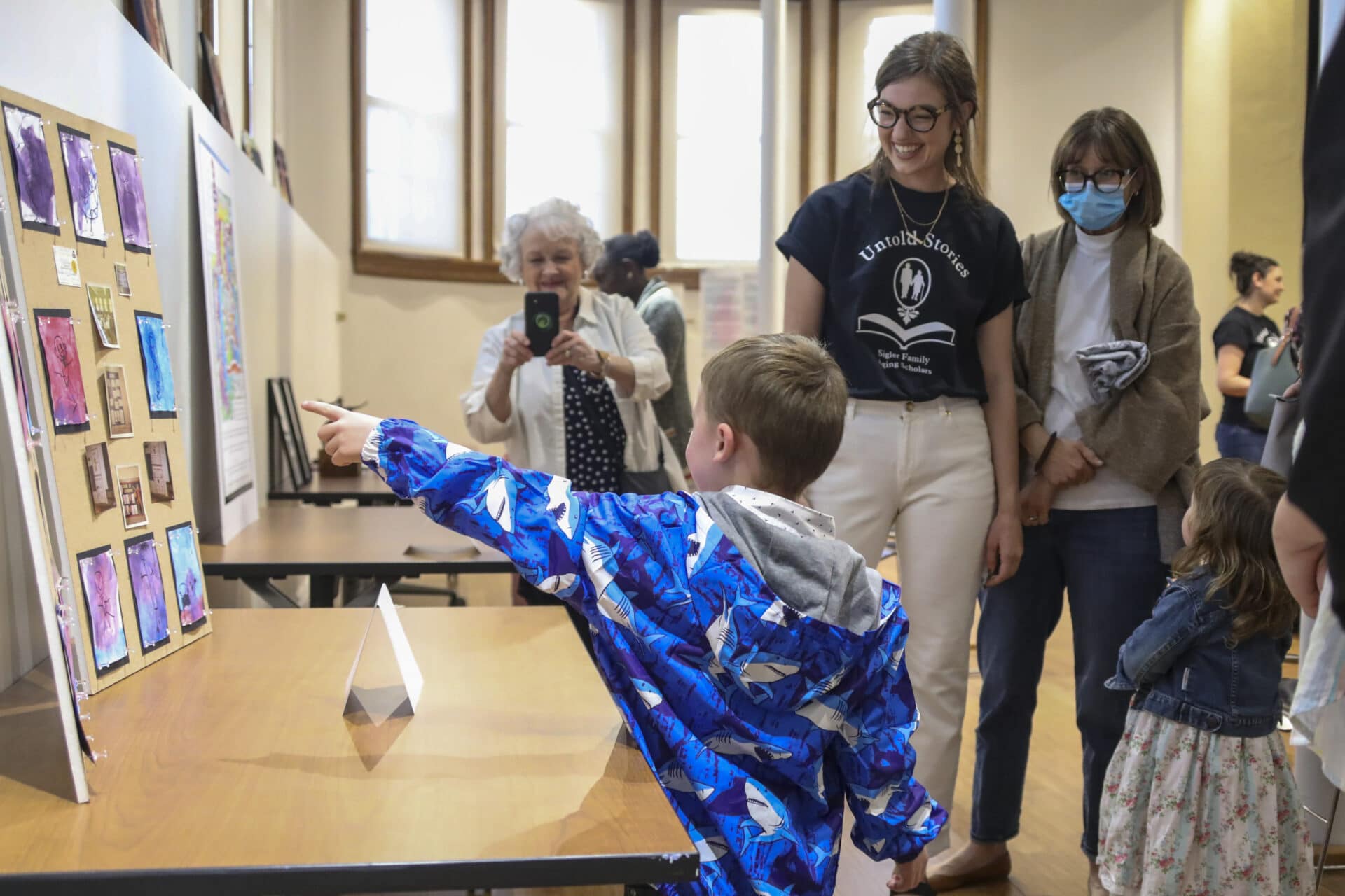 child showing a poster along with others there watching the posters present there.