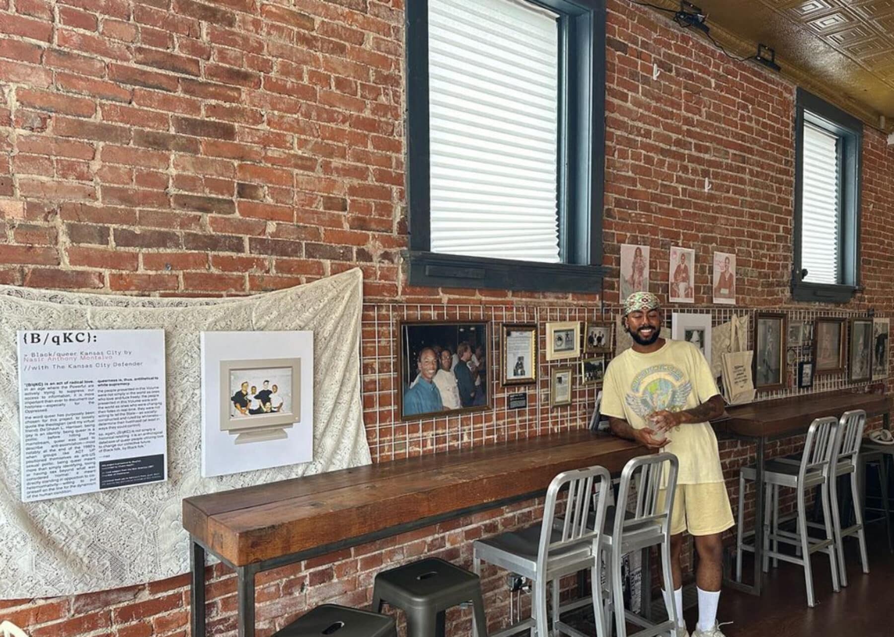 Nasir Anthony Montalvo leaning against a counter with images from the project displayed on the wall behind him